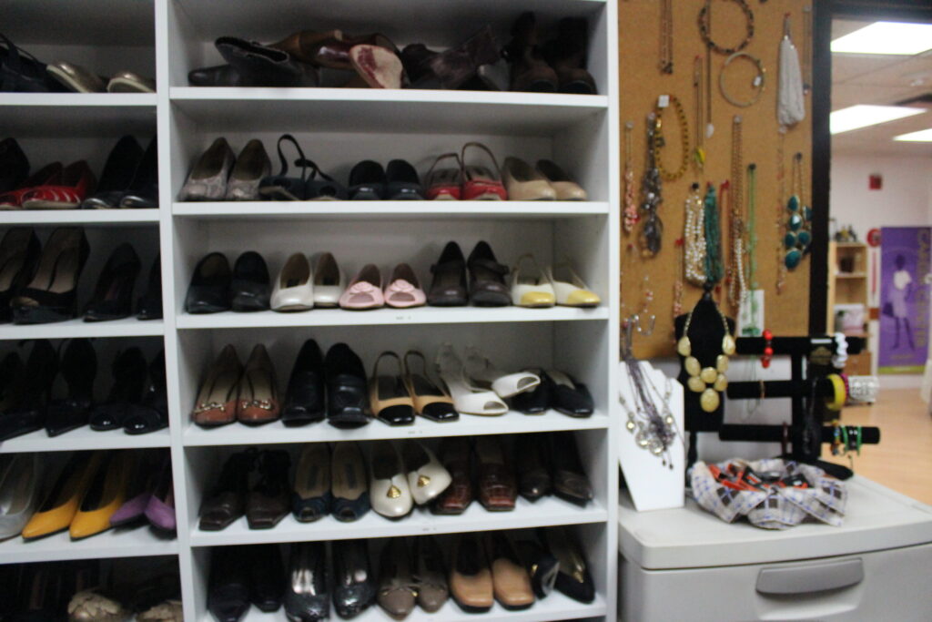 Shelves of donated shoes beside a wall of necklaces