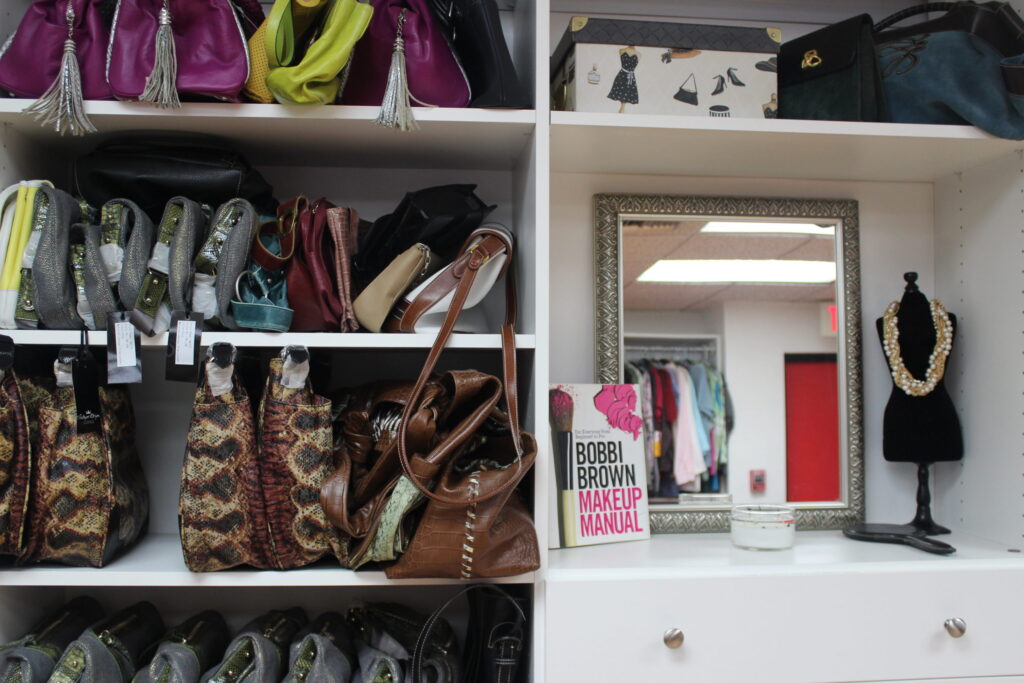 Shelves of donated handbags, a mirror and a mannequin with a necklace