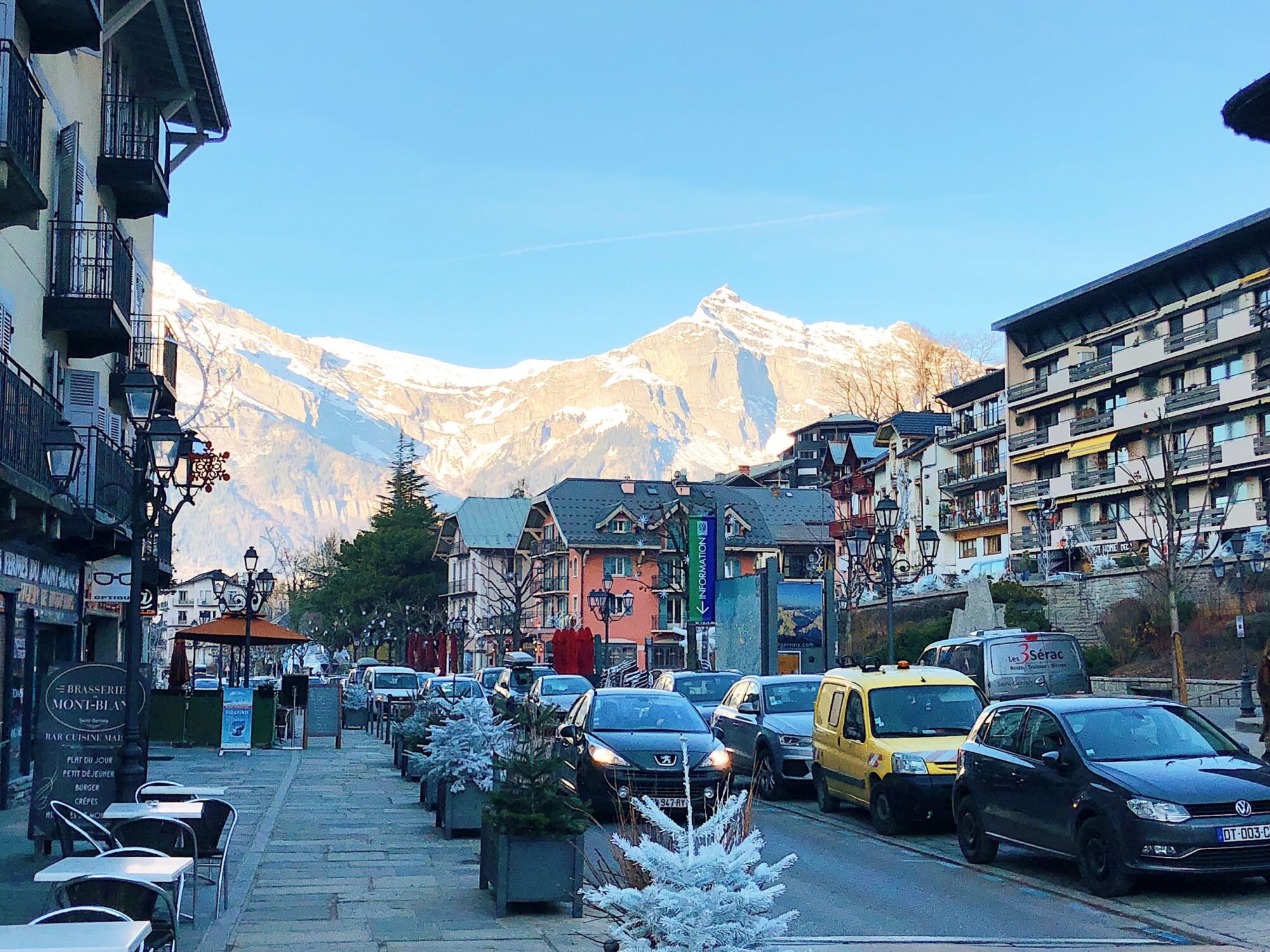 The main street of Saint Gervais-les-Bains, cars parked along it and a snow-covered mountain filling the end of the view