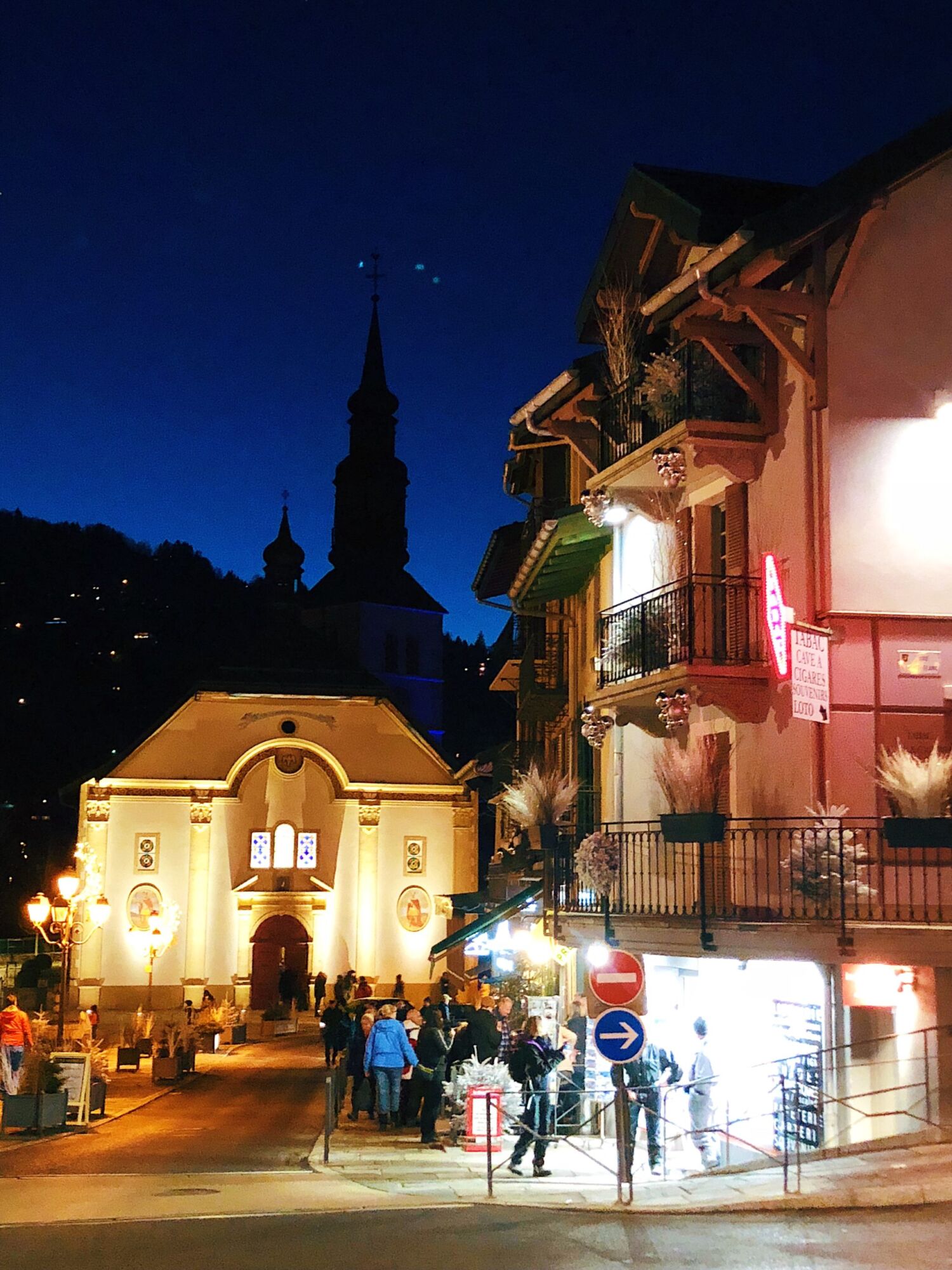 Saint Gervais-les-Bains at night, the lit façade of the church and the buildings of the square glowing against a deep blue sky