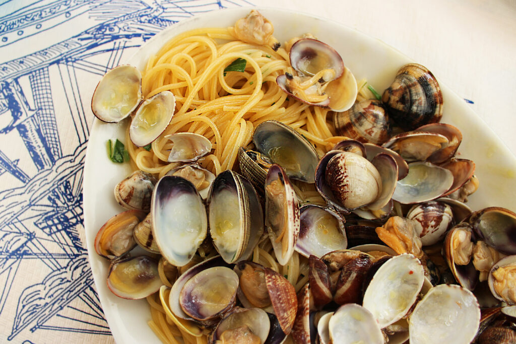 A plate of spaghetti with clams on a blue-and-white patterned tablecloth