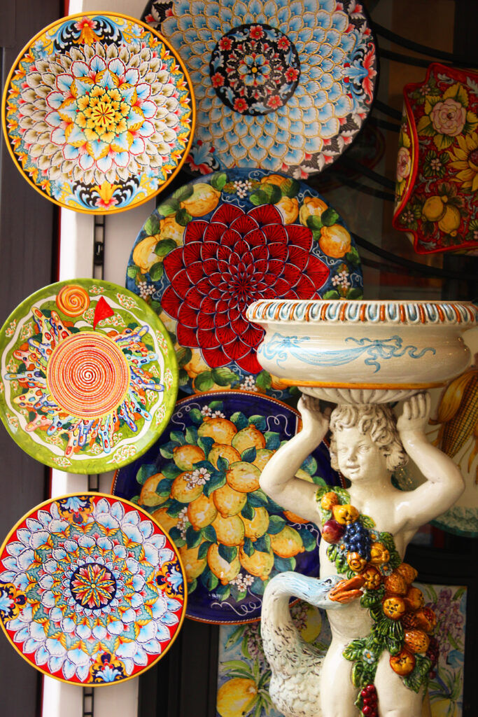 Hand-painted ceramic plates hanging on a wall above a ceramic figure holding a bowl