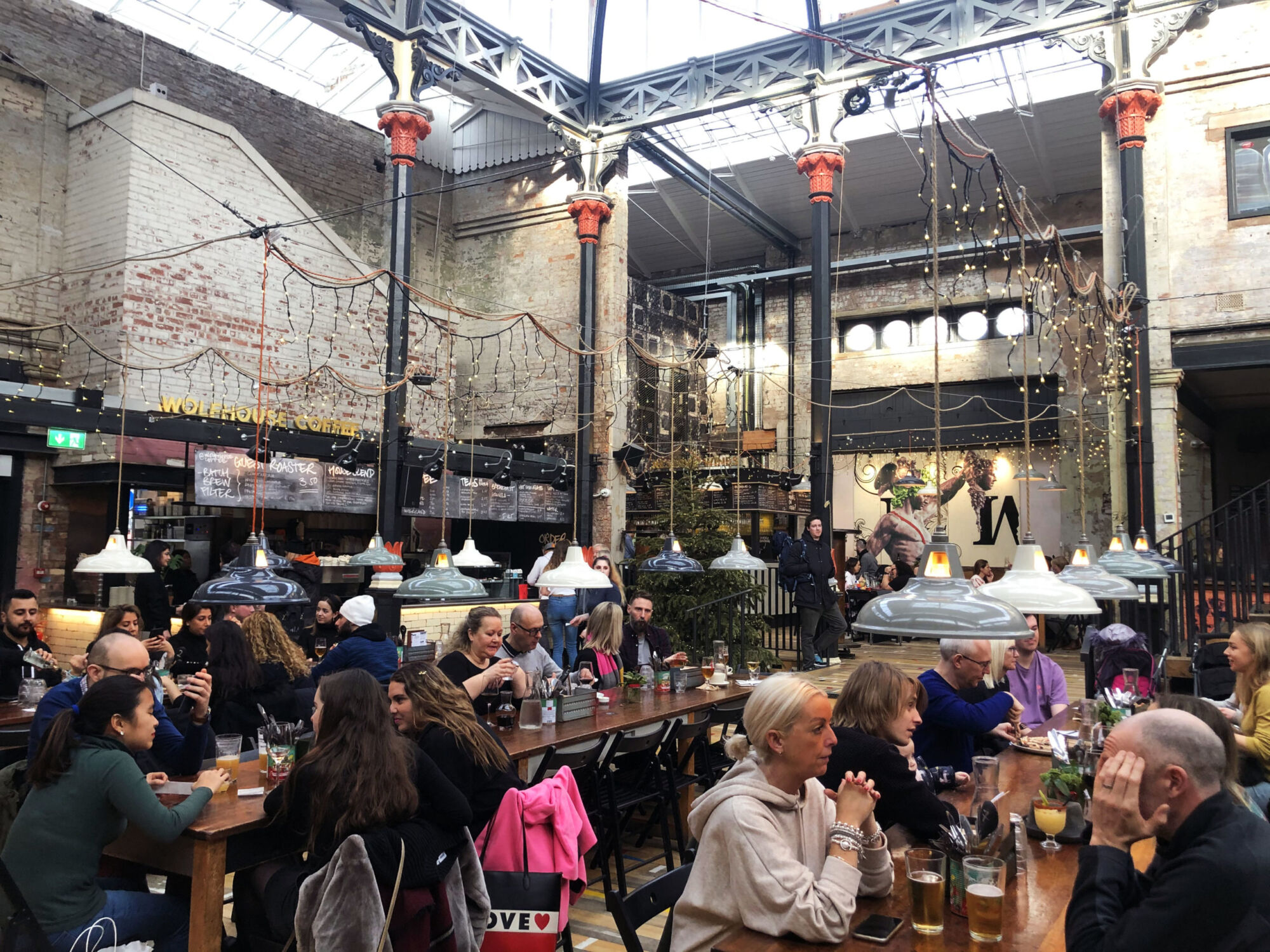 The Victorian iron and glass hall of Mackie Mayor, busy with people eating at long communal tables