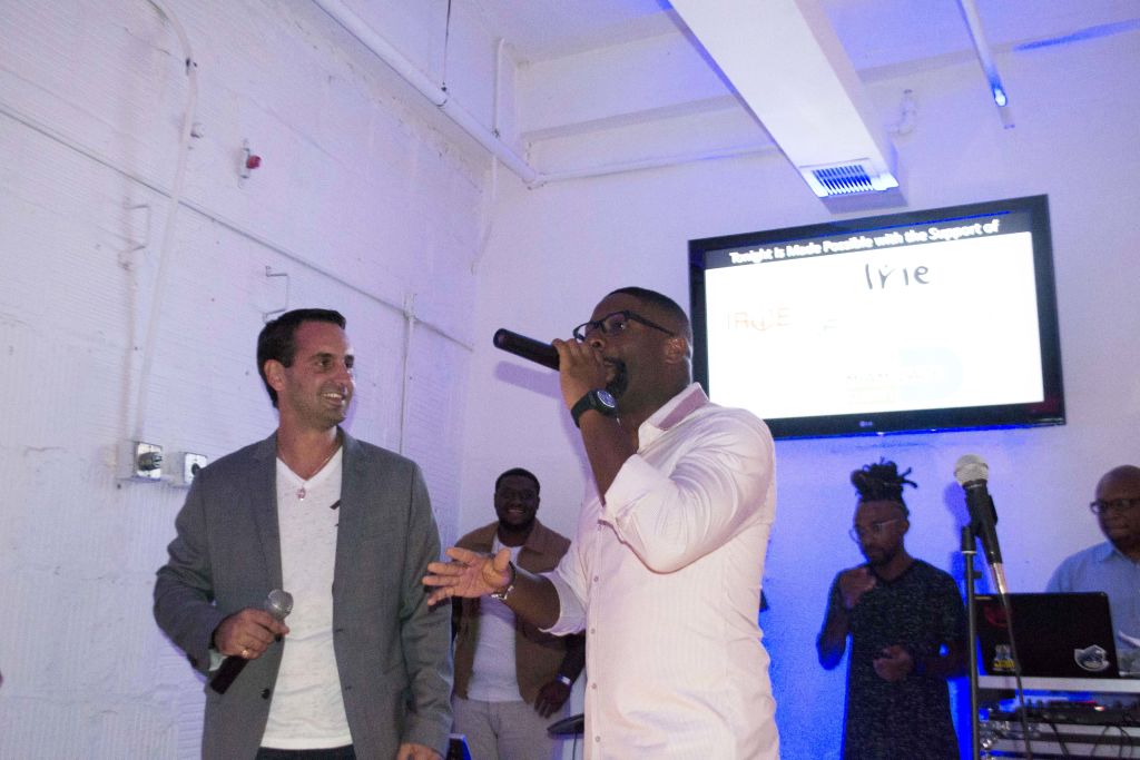 Ian Welsch and DJ Irie speaking into microphones at a student presentation