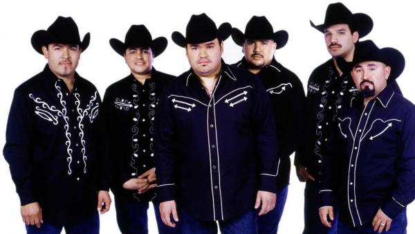 A band of six men in black cowboy hats and matching embroidered black shirts