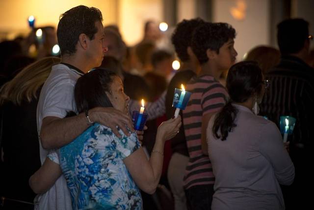 People holding candles and embracing at a candlelight vigil