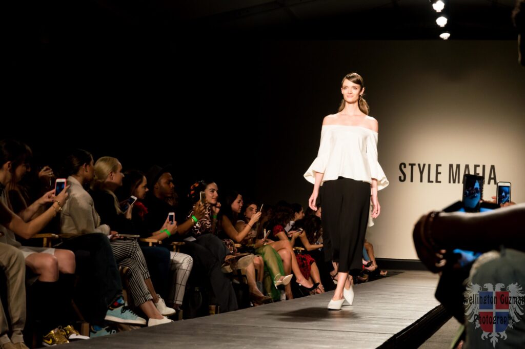 A model in an off-the-shoulder white top and black trousers on the Style Mafia runway