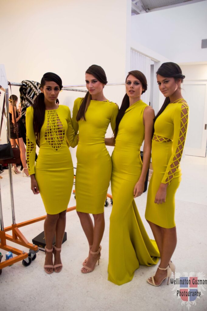 Four models in matching chartreuse long-sleeved dresses posing backstage