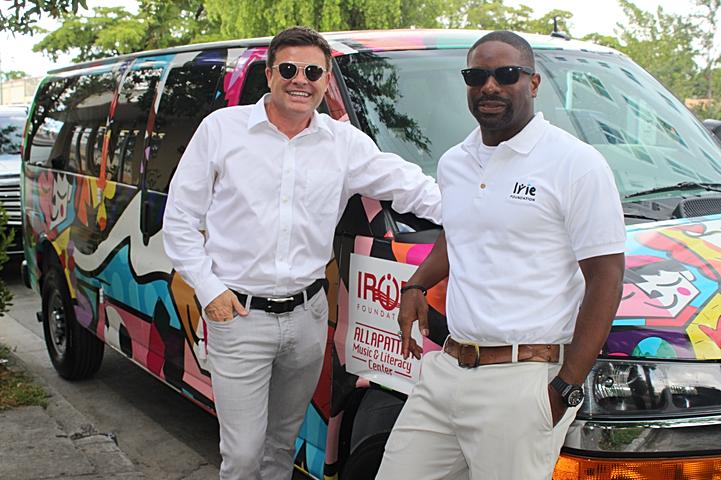 DJ Irie and a man in white shirts and sunglasses standing beside a painted van