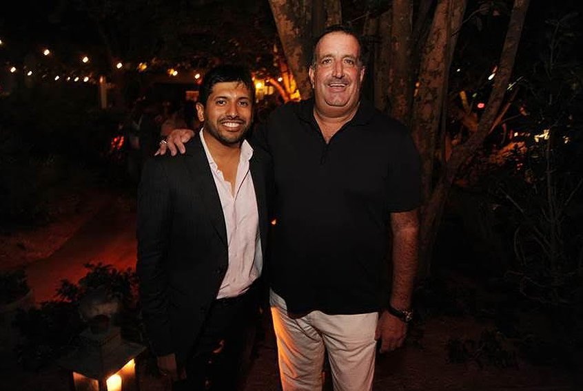 Two men posing together in a garden at night