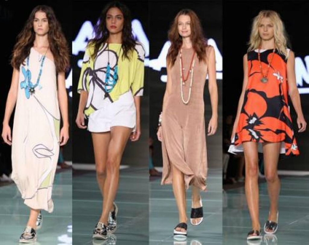 Four models in relaxed printed summer dresses and shorts on a runway