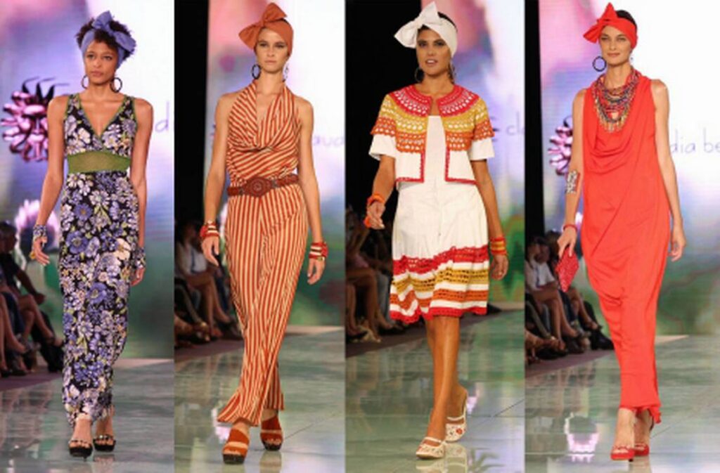 Four models in African-print dresses and headwraps in purple, orange, red and white