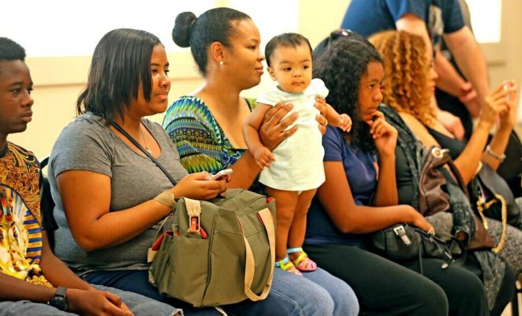Parents and a baby sitting in a row, watching a dance class