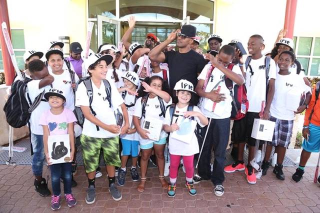 A crowd of children in Irie T-shirts and hats posing with adults outside