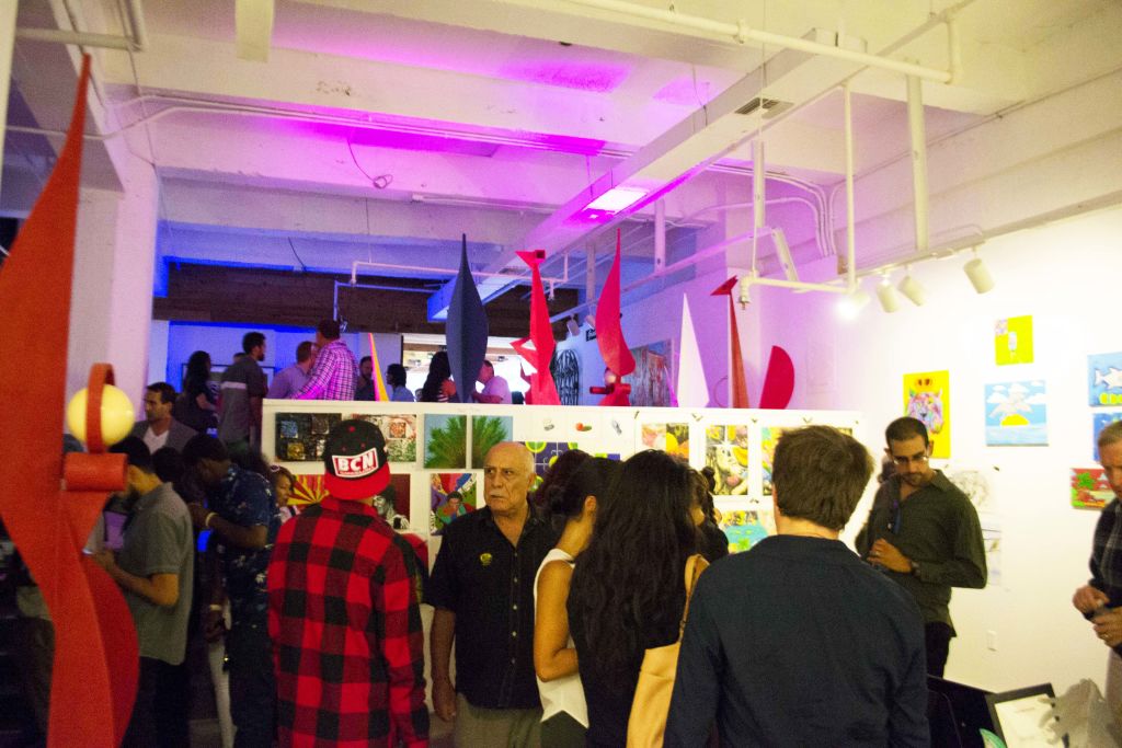 Guests looking at student artwork on the walls of a gallery