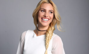 Lele Pons laughing, with a long blonde side braid and a white top