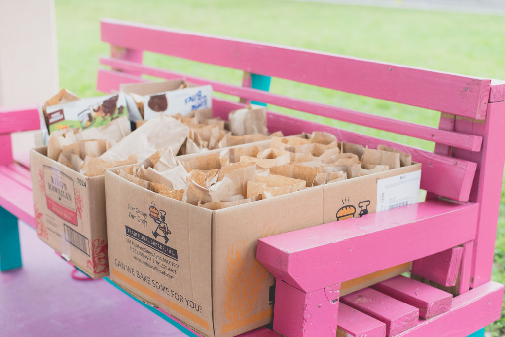 Cardboard boxes of packed lunch bags on a pink bench