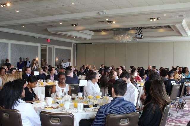 A full ballroom of guests at round tables during a luncheon