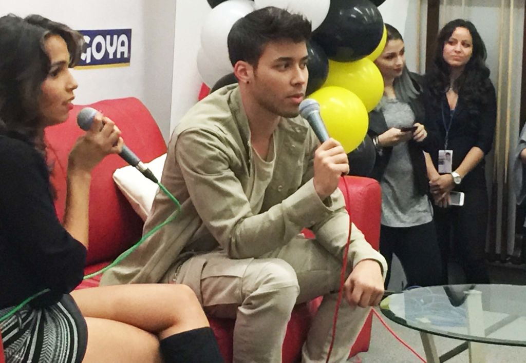 Prince Royce answering questions into a microphone beside a woman, at a fan event