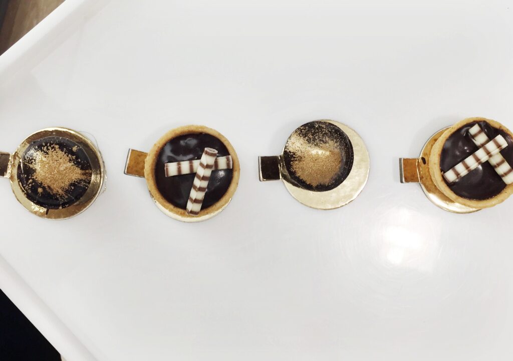 Four small round dishes of chocolate desserts on a white tray