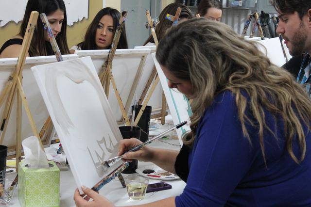 Women painting on canvases at easels during a paint-and-sip party