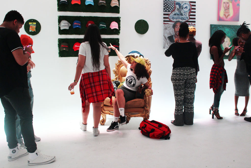 Visitors looking at art and a gold chair in a white gallery
