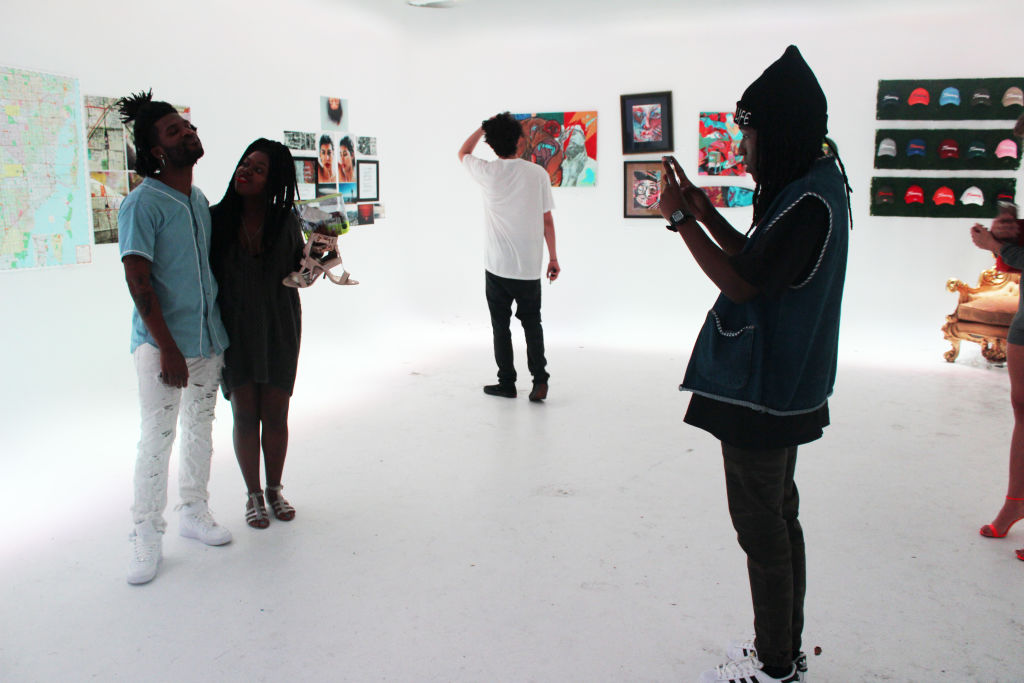 Visitors taking photos of art in a white gallery