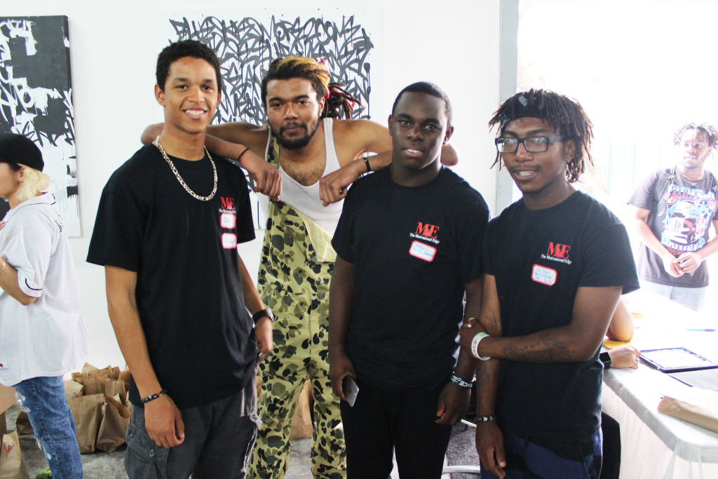 Four young men in black T-shirts posing together at a volunteer event