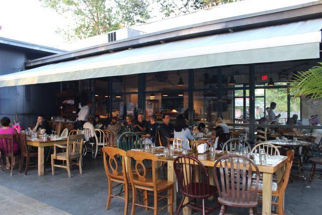 The covered patio of Ironside Pizza with wooden tables and diners