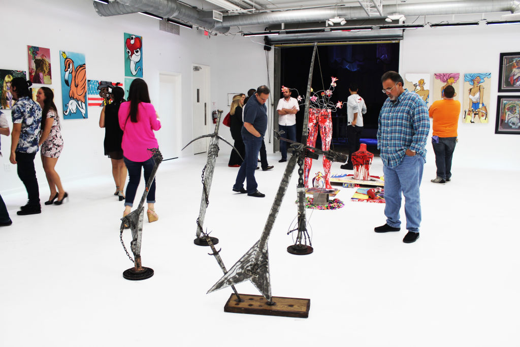 Visitors walking among sculptures and paintings in a white gallery