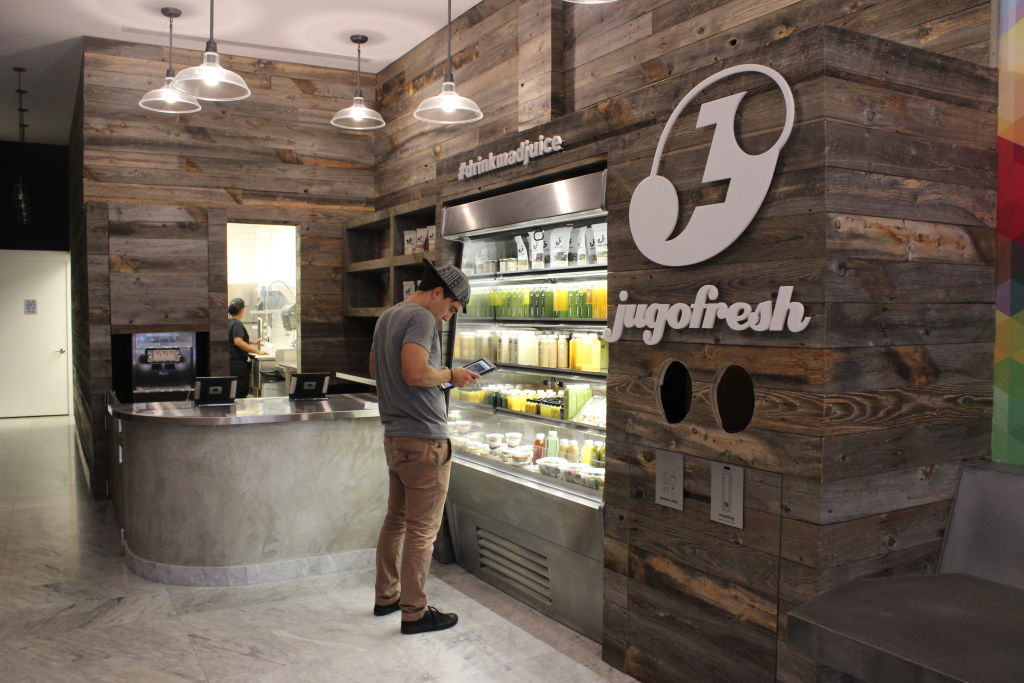 The inside of a Jugofresh juice bar with a wood-panelled wall and a chilled display