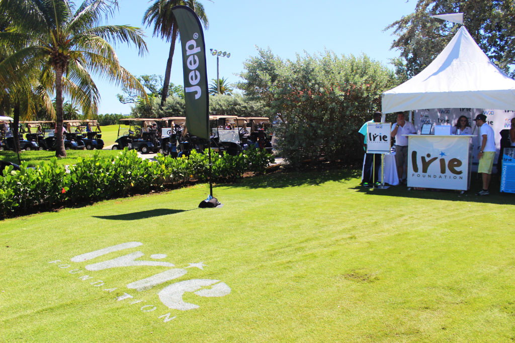 A white event tent and an Irie logo mowed into the grass on a golf course