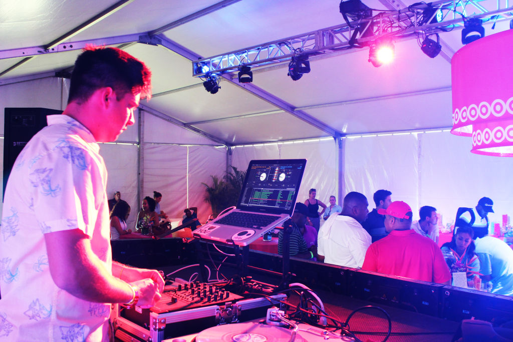 A DJ playing at a party inside a tent lit pink and purple