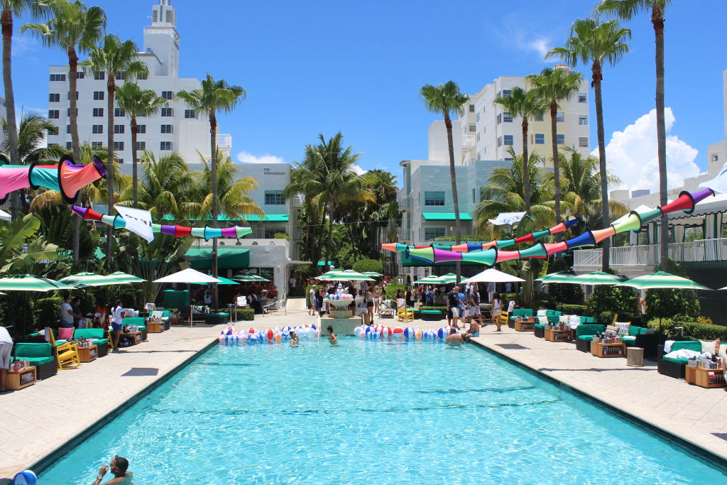 A long pool surrounded by loungers, palm trees and colourful bunting at a hotel party