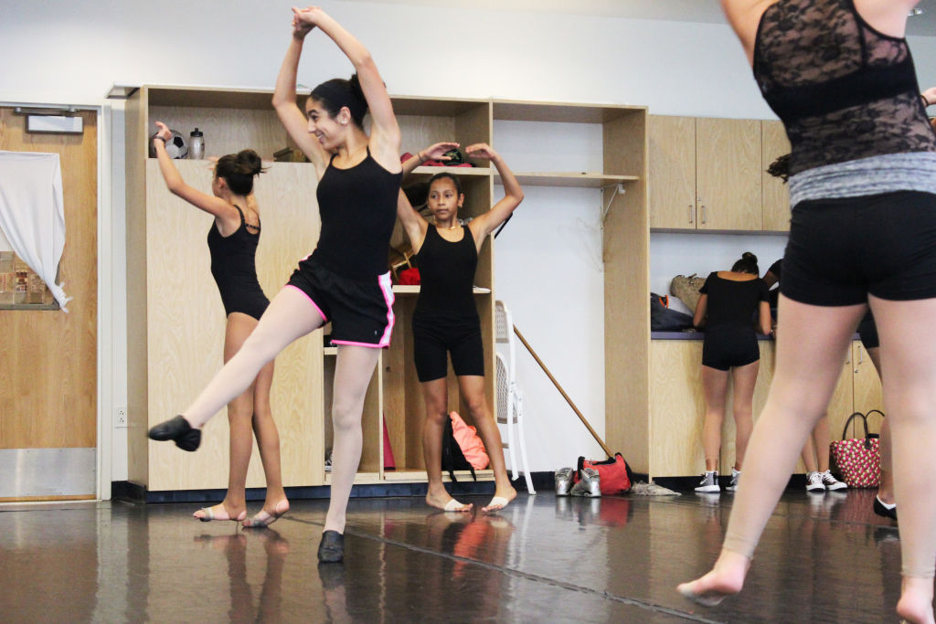 Girls in black leotards practising a pose in a dance studio