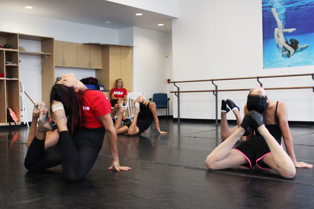 Dancers stretching in back-bends on the floor of a studio