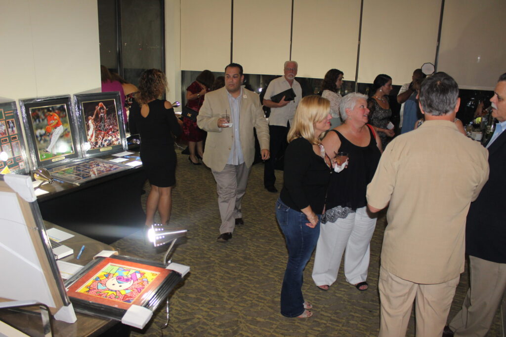 Guests mingling around a table of auction items at a gala