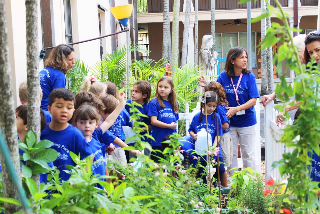 Kindergarteners and teachers gathered in a school garden among tall plants