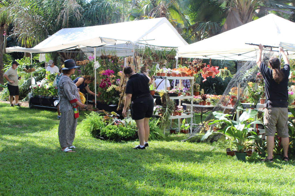 Visitors browsing plant stalls under white tents on a lawn