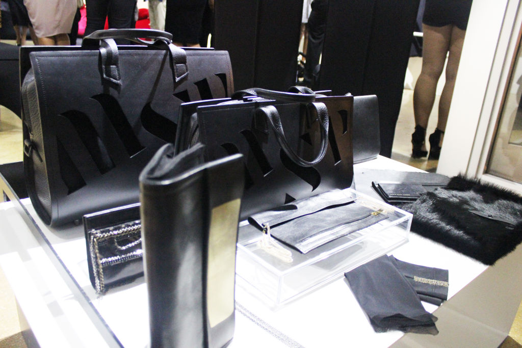 Black leather handbags and accessories displayed on a white table