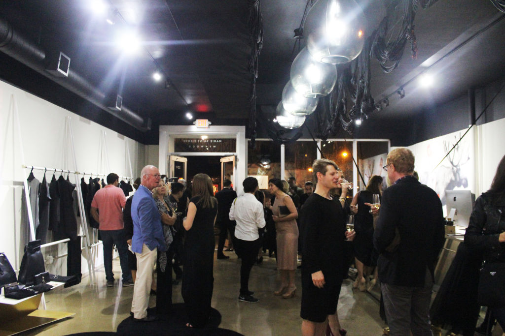 Guests mingling at a boutique opening among rails of black-and-white clothes