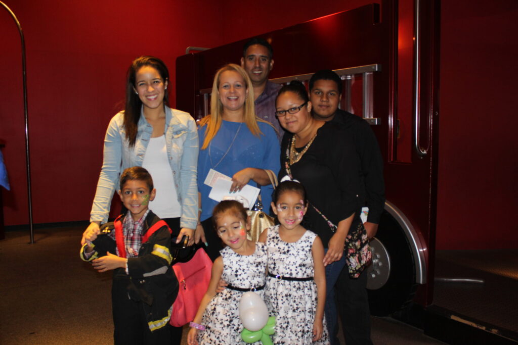A family posing in front of a red fire truck exhibit at a children's museum