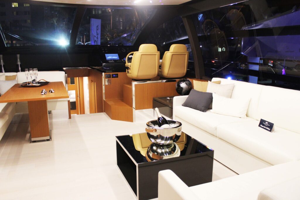 The inside of a yacht with a white sofa, cream seats and an ice bucket with champagne