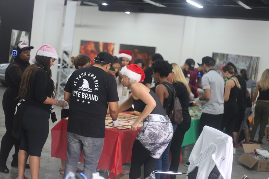 Volunteers in Santa hats packing bags at tables in a gallery space