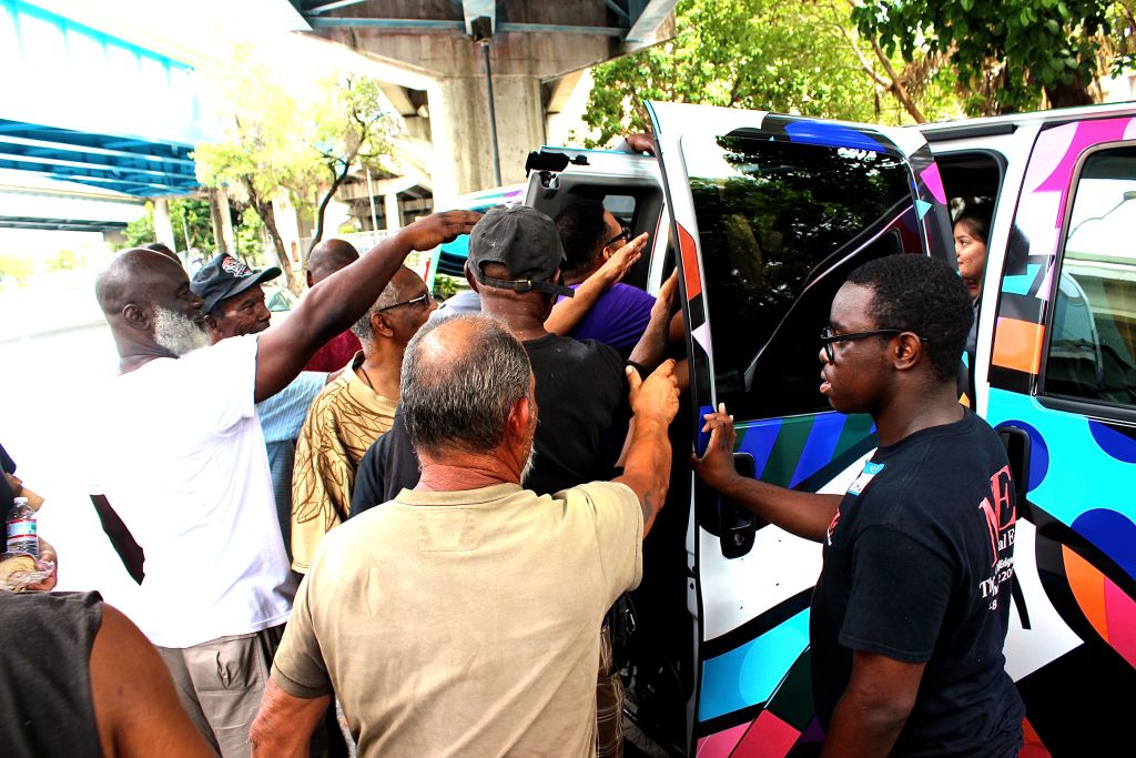 People crowding around a painted van to collect lunches on the street
