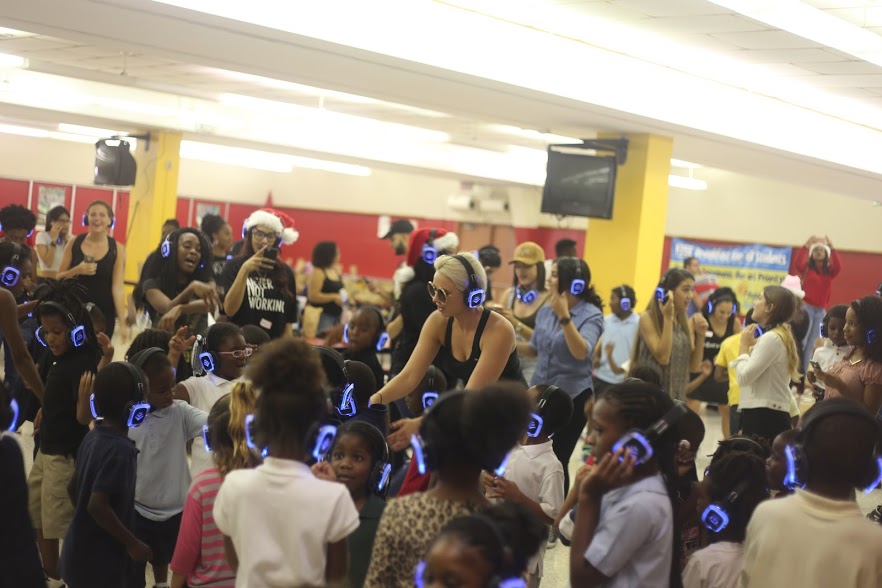 A room packed with children wearing blue-lit headphones at a party