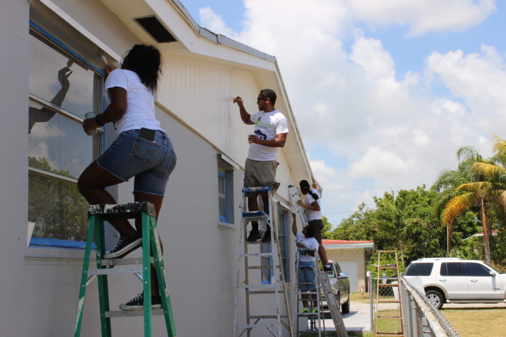 Volunteers on ladders painting the outside of a white house