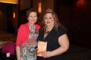 Annie Parker and a woman in a tiara holding a book, at an event