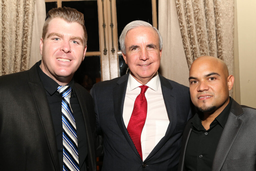 Carlos Giménez posing with two men at an evening event