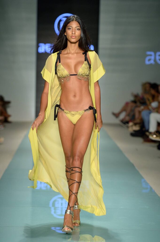 A model in a yellow bikini and long yellow cover-up on a Swim Week runway
